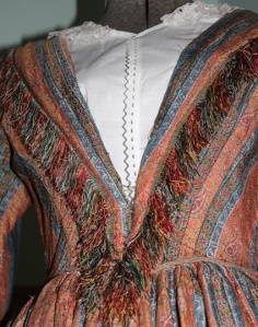 A woollen dress is woven in a stripe design of blue and orange with silk fringe.
